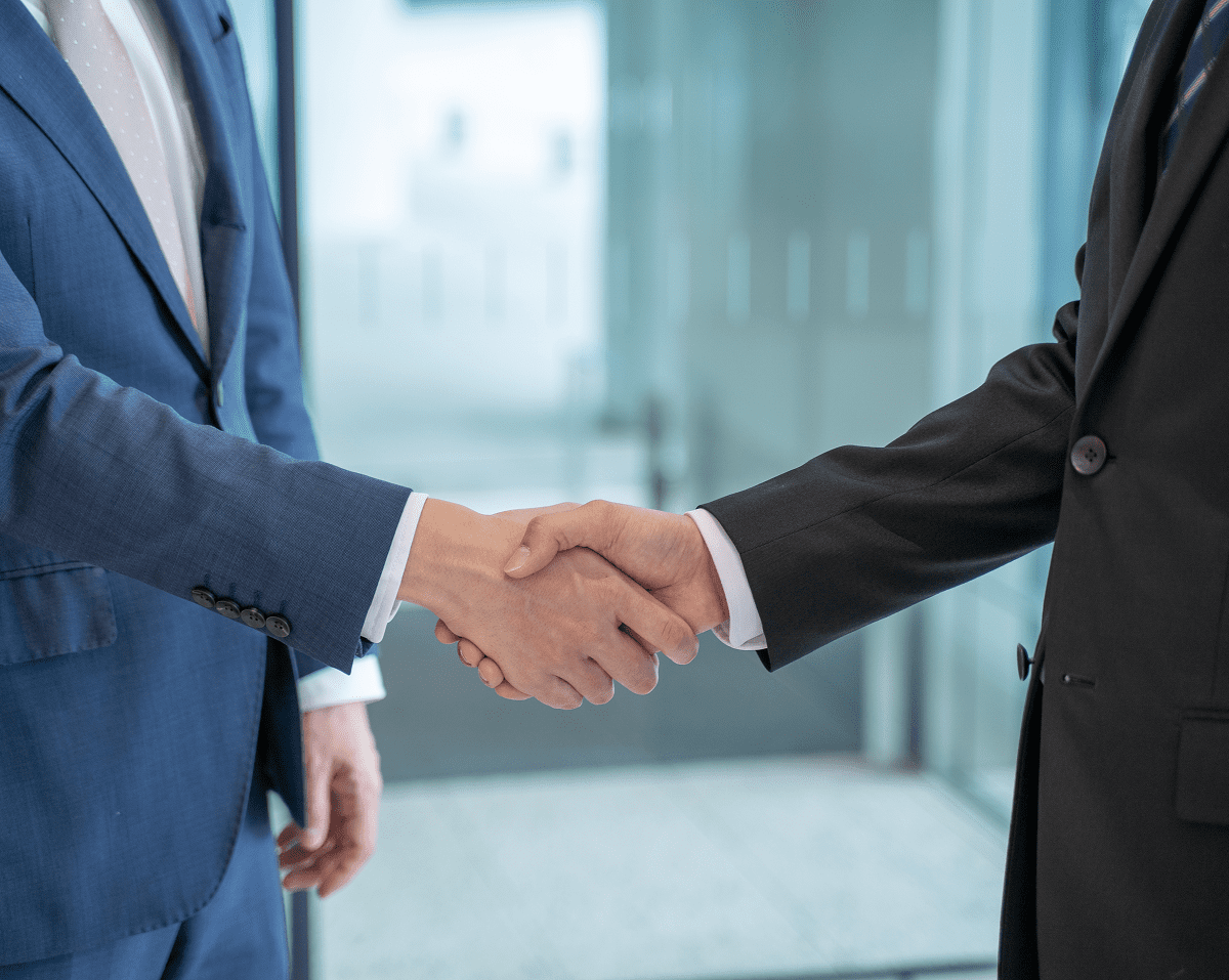Two people shaking hands in suits.